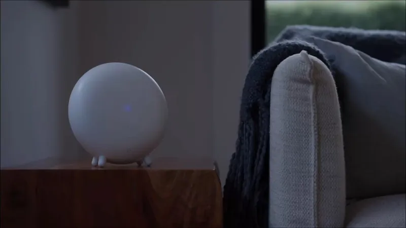 The jupyter Indoor Halo glowing on a timber side table beside a sofa, from the film The home that protects itself